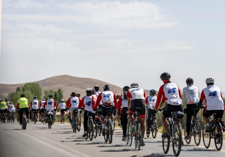 Group of cyclists in sportswear racing on a scenic road near hills.