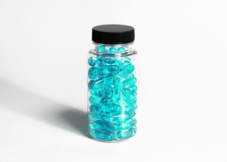 A clear bottle filled with turquoise capsules, showcasing healthcare and nutrition themes.